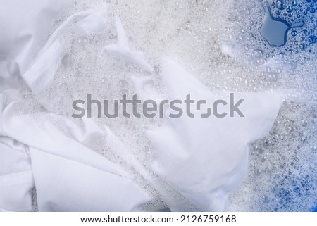 White garment in suds, closeup. Hand washing laundry
