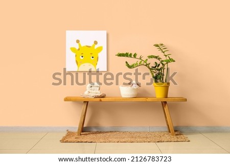 Table with knitted sweaters and houseplant near color wall