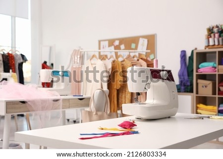 Sewing machine and accessories on table in dressmaking workshop Royalty-Free Stock Photo #2126803334