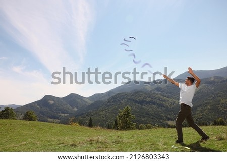 Man throwing boomerang in mountains on sunny day. Space for text Royalty-Free Stock Photo #2126803343