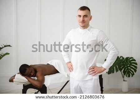 Portrait of young massage therapist in white clothes on white background, copy space