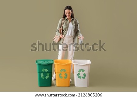 Young woman sorting plastic bottle and paper on color background Royalty-Free Stock Photo #2126805206