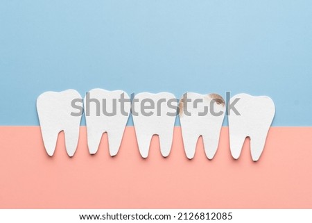 Decayed tooth among good tooth cartoon made from paper. Common problem lead to a severe toothache, infection and tooth loss. Dental care concept.