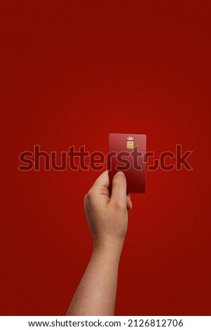 Hand holding credit card with red background and copy space. Background of credit card as template for cutting out.