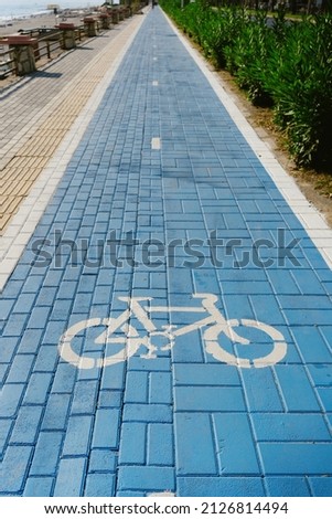 Symbol to indicate the road for bicycles. Blue path among green bushes