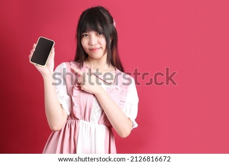 The teen Asian girl with cute Japanese costume standing on the red background.