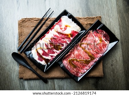 fresh raw pork, meat ,beef, belly, sliced on square plate  on fabric and wood, wooden background, shabu, hot pot ingredients.
