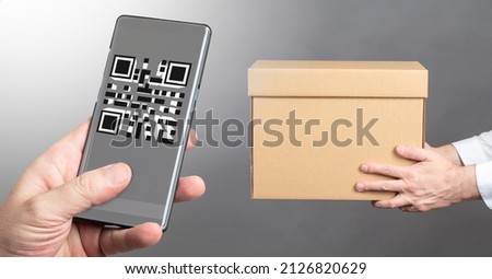 Cardboard box in hands of man. Tracking parcel using barcode in phone. Concept of receiving parcel using QR. Using QR to identify person. Demonstration of QR code to receive delivery.