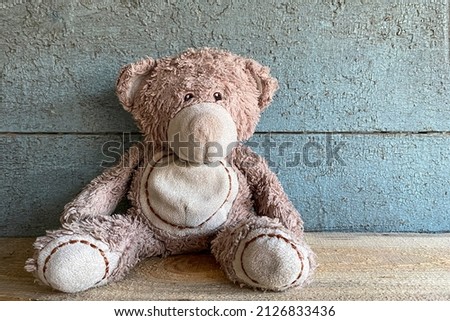 Old toy bear. Old cracked blue background.Old wooden background. Place for text