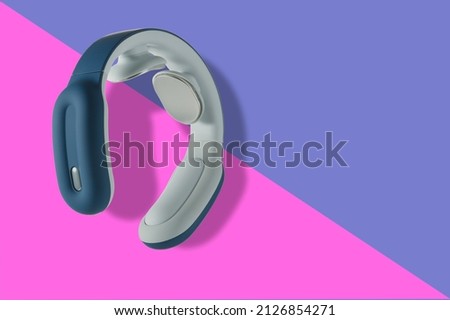 Compact pulse electric smart neck massager on a blue background. High quality photo. Copy space