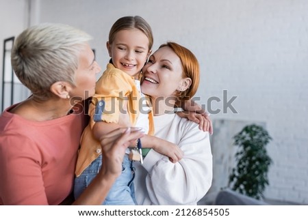 blurred lesbian woman holding key from new apartment near girlfriend and adopted daughter Royalty-Free Stock Photo #2126854505