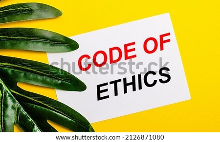 White sheet of paper with the inscription CODE OF ETHICS on a bright yellow background near the green leaf of the plant. Eco natural banner concept