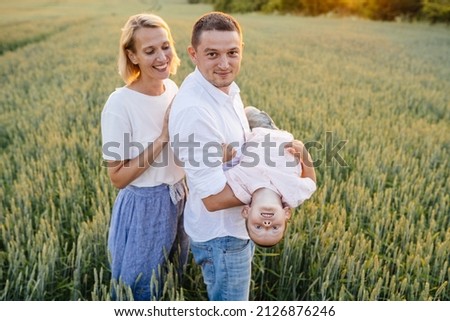Man and woman with kid playing having fun in wheat summer field at sunset. Holidays with children in the countryside. Beautiful sunset. Family vacation concept.