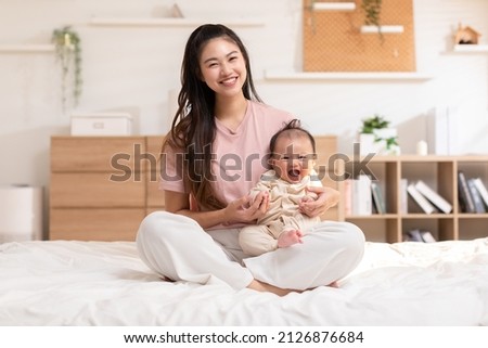 Adorable newborn baby smile and relax in mother arm safety and comfortable.Healthy Asian newborn infant baby laughing with happiness good moment.Mother holding infant baby.Newborn Baby concept Royalty-Free Stock Photo #2126876684