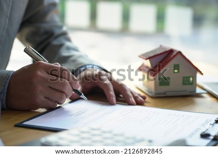 The businessman sign a contract and architectural style of the house.