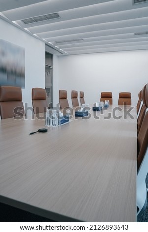 Business meeting room or Board room interiors.Orange chairs and wood-grain conference tables inside. Royalty-Free Stock Photo #2126893643