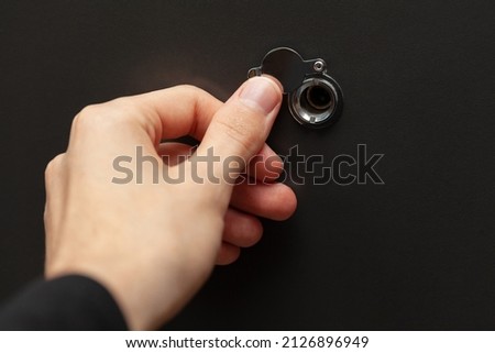 Anonymous man taking a peek, looking through a peephole checking the door, sneak peek, curiosity. Uncertainty, foresight and home safety measures simple abstract concept, home isolation, nobody Royalty-Free Stock Photo #2126896949