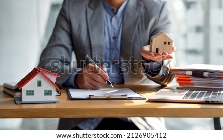 Close up house model mortgage loan with businessman real estate broker signs a purchase contract or mortgage for a Home Interiors, real property estate concept.