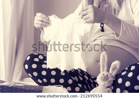  pregnant woman holding a  baby dress 