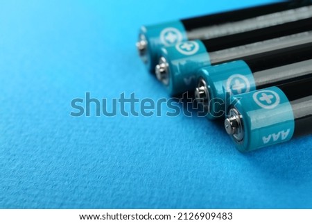 New AAA batteries on tuquoise background, closeup. Space for text Royalty-Free Stock Photo #2126909483