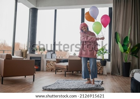 A happy girl dancing wiht a bunch of colorful balloons