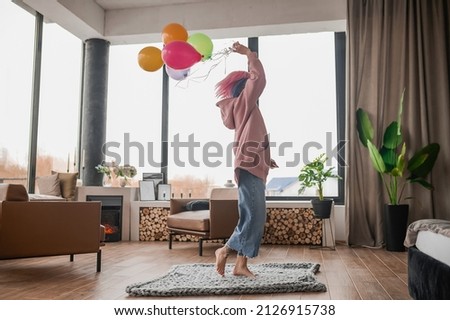 A happy girl dancing wiht a bunch of colorful balloons