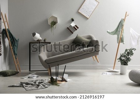 Chaotic living room interior during strong earthquake Royalty-Free Stock Photo #2126916197