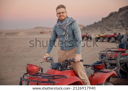Man tourist with arafatka on quad bike ATV safari in desert Arab Emirates, Egypt.