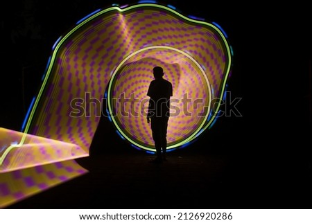 one person standing against beautiful yellow green and red circle light painting as the backdrop
