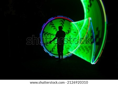 one person standing against beautiful blue green and red circle light painting as the backdrop
