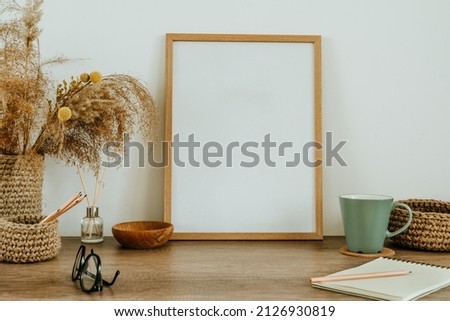 Empty wooden picture frame and dried flowers pampas grass in the jute vase on the wooden table with blank space for text. Natural materials using at cozy home decor. Eco friendly concept.