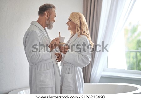 A happy mid aged couple in white robes feeling wonderful Royalty-Free Stock Photo #2126933420
