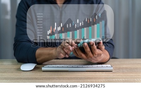 Hand of Businessman or trader is showing a growing virtual hologram stock on smartphone, planning and strategy, Business growth, Stock market, progress or success concept. invest in trading at wooden.
