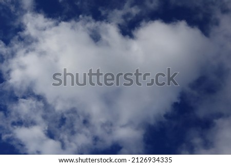 A heart-shaped white cloud in the blue sky