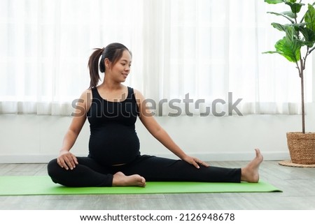 A pregnant woman doing stretching sports Healthy life expectancy in a living room with natural light.