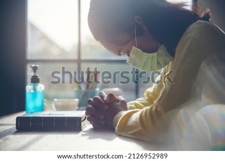 Asian woman wear mask, Christian worship pray, and hope for peace world, and free from coronavirus, Hand in hand together on bible, believes and faith in christian religion at church. Prayer concept. Royalty-Free Stock Photo #2126952989