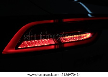 Rear red car LED lights in the dark. Bright modern car headlights on a black background. Background bright red LED car taillights in the dark. Diode stop light. 