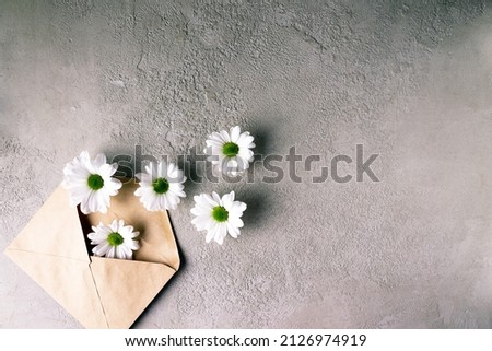 craft paper envelope with white daisies on gray stone, copy space