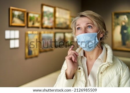 female visitor looking at artwork painting in the museum indoors
