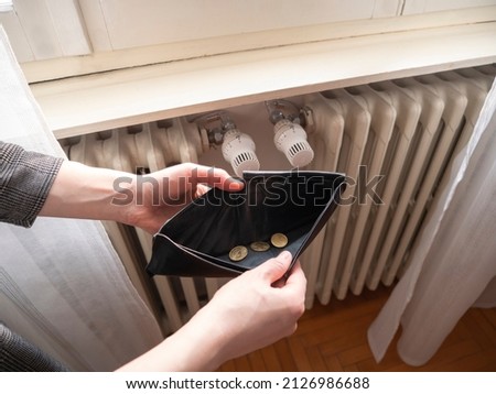 Heating bill. Increase in the cost of gas bill. Soaring energy prices. Increase in the price of natural gas. Energy crisis in Europe. Hands hold wallet with money near the radiator. Pay the bills. Royalty-Free Stock Photo #2126986688
