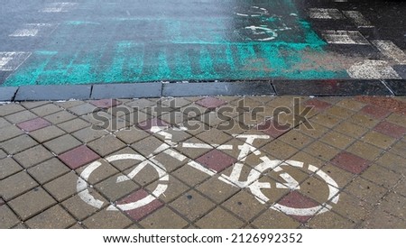 Concept traffic sign. White bike lane sign on wet sidewalk. Bicycle markings. The bicycle sign is painted on the pavement with white paint.