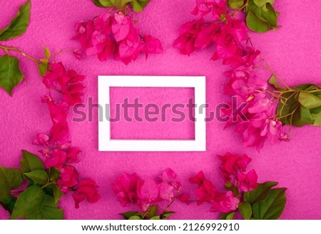 Flowers composition. Empty photo frame and flowers on pink background. Valentines day, mothers day, women day, spring concept. Flat lay, top view, copy space.