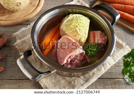 Ingredients for preparing beef broth or soup - marrow bones, carrots, savoy cabbage and parsley in a pot of water