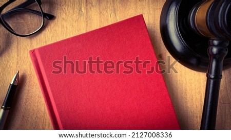 Top view of blank red cover book with gavel as background.