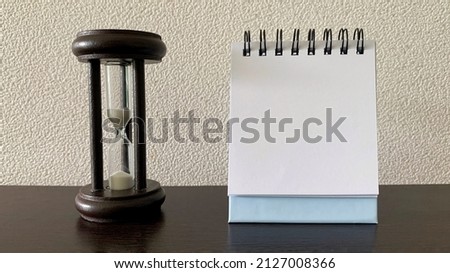 Straight view of blank notepad with minutes glass background.