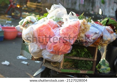 Picture of some merchandise from a vegetable seller at the market in the morning, the merchandise is hanging haphazardly on the rack on the motorbike
