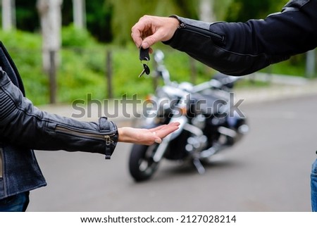 Man with gloves holding a key with motorcycle background.Motorcycle buying concept Royalty-Free Stock Photo #2127028214