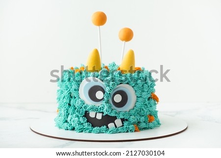 Monster theme cake on the white background. Birthday cake with turquoise fluffy cream cheese frosting Royalty-Free Stock Photo #2127030104