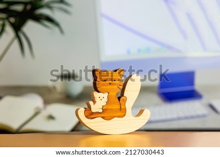 Wooden puzzle in the form of a handmade cat family on the background of a computer table