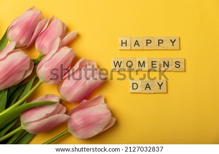 International Women's Day. Beautiful postcard for March 8. Spring bouquet of pink tulips with the inscription Happy Women's Day on a yellow background. Holiday concept. Copy space. Flatley
